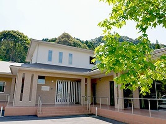 ２階建ての建物の外観写真。エントランス部分にスロープがついている様子