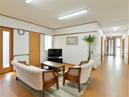 デザイン性の高いソファとテーブル、テレビが置いてある施設内のリラックススペースの様子