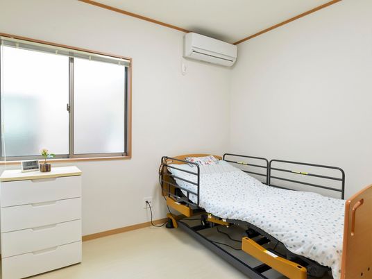 介護用ベッドと小さな箪笥、エアコンなどがついている施設内の居室
