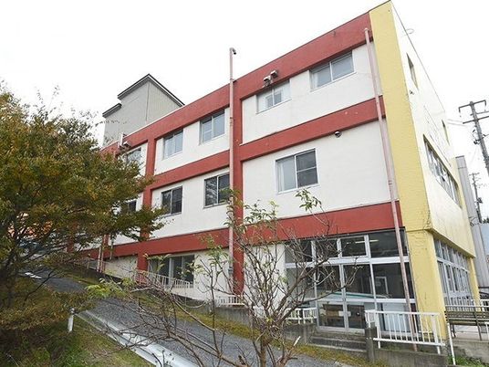 3階建ての建物はコンクリート製でどっしりとした頑丈な建物。白を基調に赤いラインが入っている。