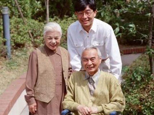 車いすを押すスタッフと一緒に歩く夫婦。外に出て何かを眺めてリラックスしている様子