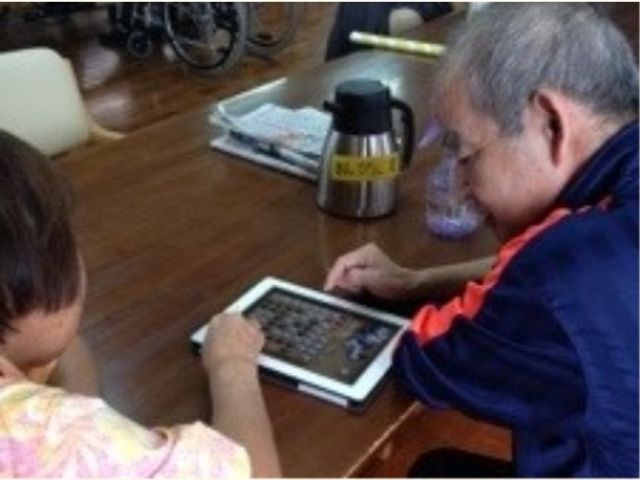 iPadを使ったオセロのレクリエーションの様子です。のんびりと、思い思いの時が過ごせるくつろぎのリビングです。