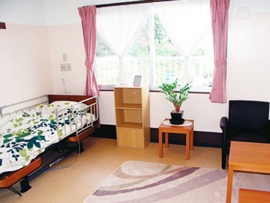 カーテン付きの大きな窓がある部屋には棚や寝具付きのベッド、ソファなどがあり、緊急通報装置もある。