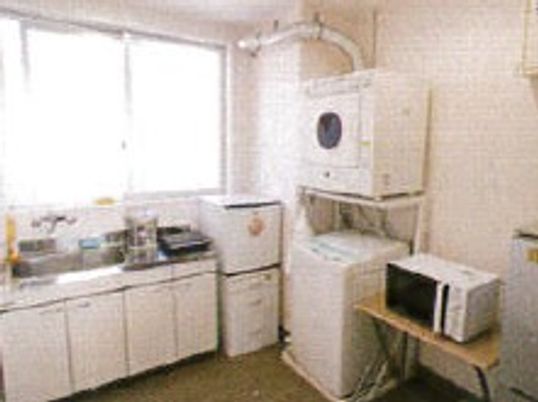 白を基調としたキッチンには白い冷蔵庫・洗濯機・乾燥機・電子レンジなども置かれている。