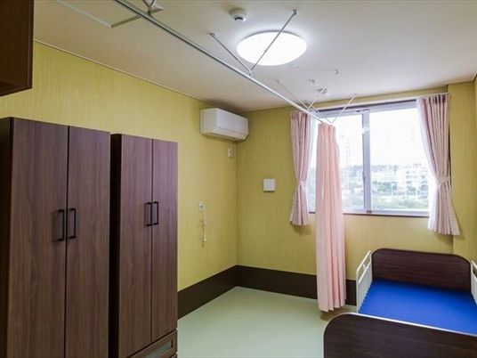 居室にはベッドと収納棚が置かれ、大きな窓があり明るい雰囲気。