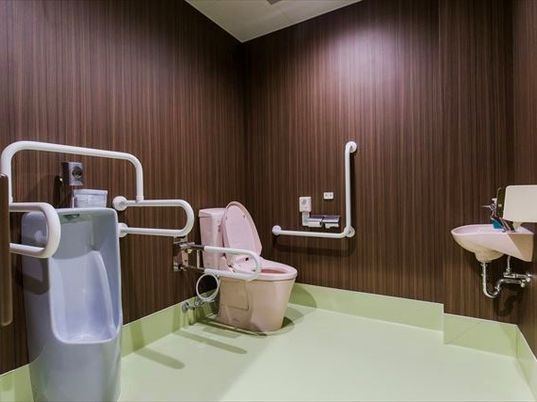 男性専用のトイレとシャワー付きトイレが並んで置かれた広いトイレ。介助用のスペースも十分ある。