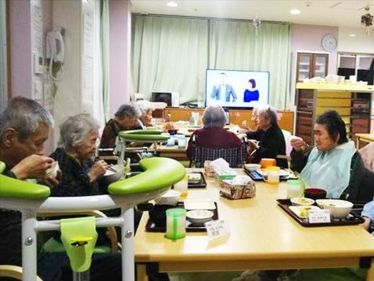 食堂に集まって食事をする入居者の様子。スプーンや箸を使って自分で食べている。