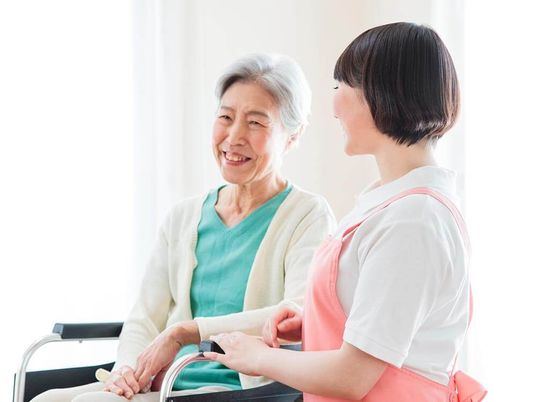 車いすの女性に寄り添うスタッフと穏やかな表情の高齢者の様子。やわらかい表情を見せている写真