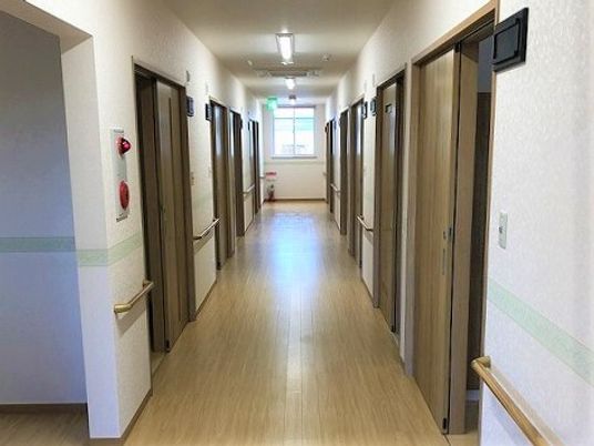 廊下は両サイドに手すりがあり、居室のドアも並んでいる。突き当りには窓があり、明るい。