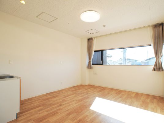 フローリングの居室は広く、大きな窓にはカーテンが付いている。