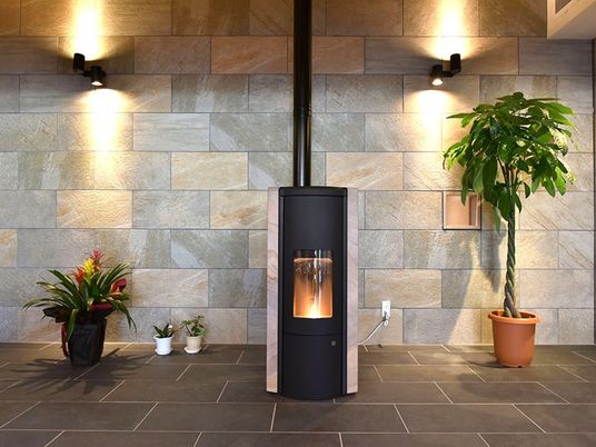 暖炉のぬくもりが感じられるスペース。壁はレンガ調で、観葉植物なども置かれている。