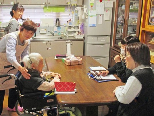 施設の利用者と会話を交わすスタッフの様子。施設内の共有スペースでの一コマ