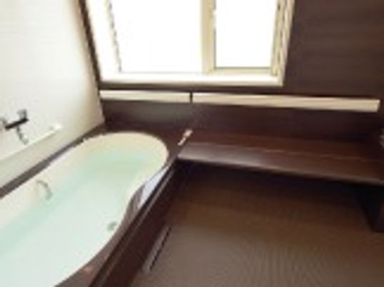 シンプルかつモダンな浴室。白い浴槽が設置された個浴は大きな窓が付いている。