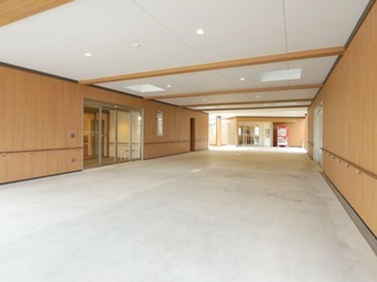 広いエントランスは白と木目調でまとめられ、出入り口は幅の広い自動ドア。