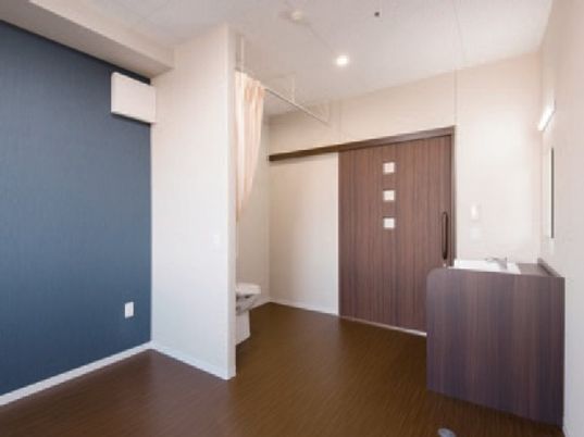 カーテンで仕切られているトイレがついた居室。シンプルな居室には洗面所もついている。