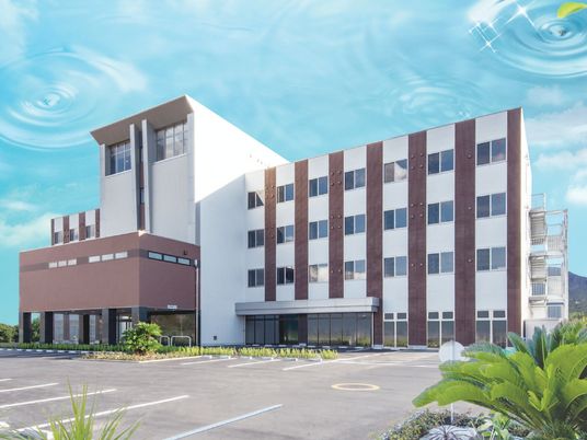 青空の下白を基調とした施設の外観が際立って見える。4階建ての建物は災害にも強い頑丈な造り。