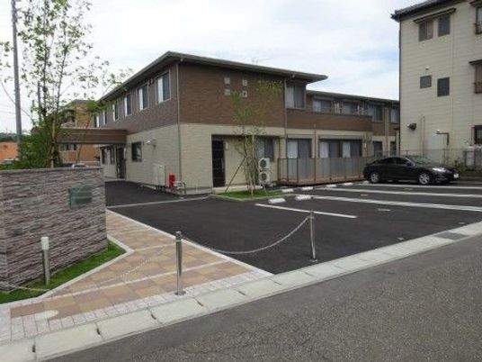 広い駐車スペースがあり、レンガ調のブロックが敷き詰められた歩道を行くと、2階建ての建物がある。