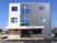 3階建ての建物はグレーと白のはっきりとした色使い。玄関先にはプランターが置かれている。