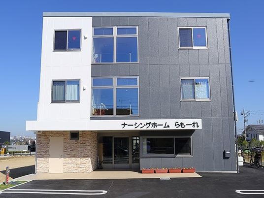 3階建ての建物はグレーと白のはっきりとした色使い。玄関先にはプランターが置かれている。