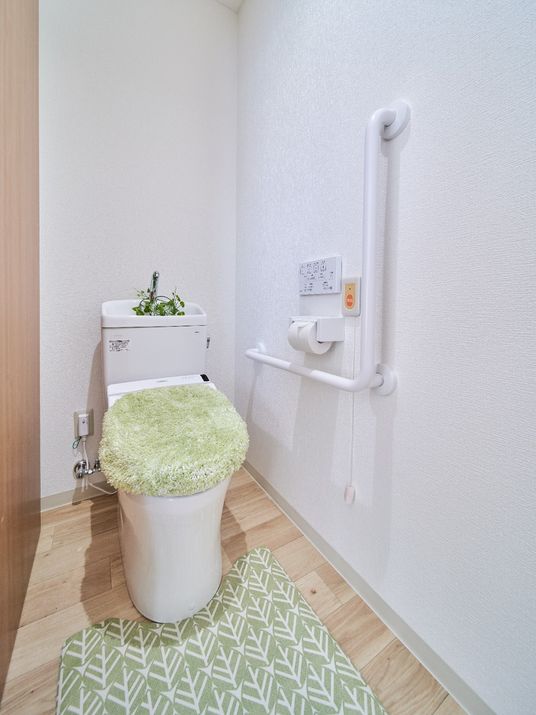 L字型の手すりが取り付けられた施設内のトイレの様子。家庭用サイズのトイレ