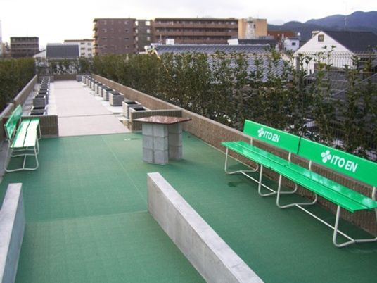 まっすぐな散歩道が設置された屋上スペース。緑のベンチも複数置かれている。
