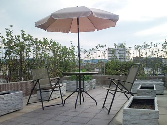 パラソル付きのテーブルセットが置かれた屋上は季節の木や花が植えられている。