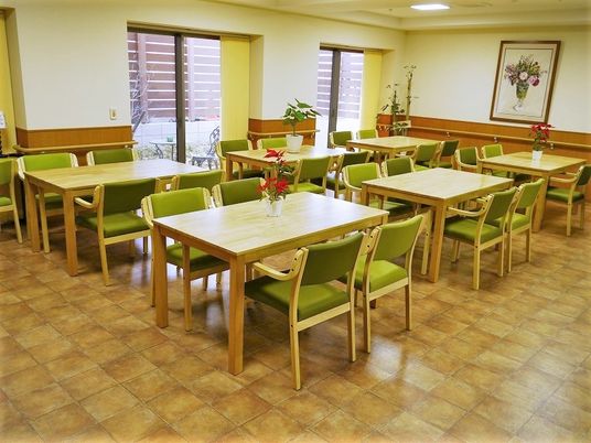 グリーンの椅子が設置された４人掛けのテーブルセットが置かれた食堂には絵画や花も飾られている。