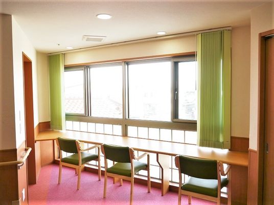 大きな窓が設置された共有スペース。窓辺に花がテーブルと椅子が置かれ、景色を楽しむことができる。