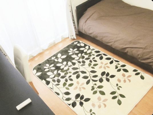 リーフ柄のカーペットが敷かれたフローリングの居室にはベッドやテーブルもある。
