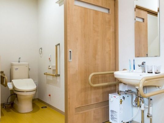 手すり付きのトイレと洗面台が写っている写真。居室内の設備の様子
