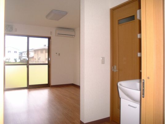 洗面所やエアコンが付いたフローリングの居室には大きな窓があり、カーテンは付いていない。