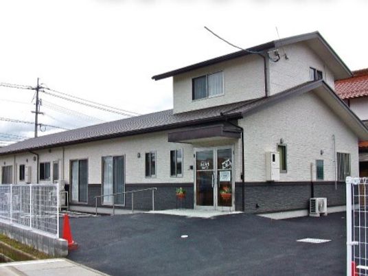 グレーの屋根が付いた２階建ての建物は玄関に屋根があり、２階部分の面積はかなり小さい。