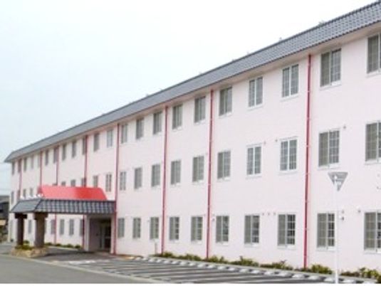 3階建ての建物は薄いピンクで玄関には大きな車寄せも付いていて、駐車場もある。