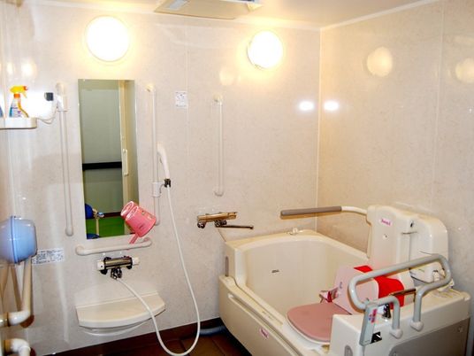 白い浴槽にはリフトなどが設置され、シャワーの周りには手すりがある。