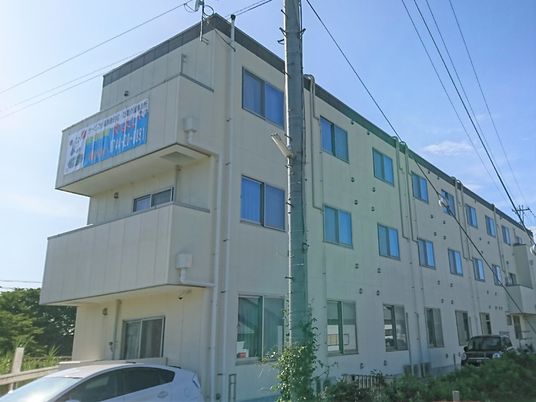 クリーム色の外観をした３階建ての建物。居室数は多く、たくさんの窓が均等に並んでいる。