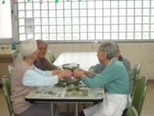 向き合って会話している施設内の高齢者の様子。日常の一場面を写した写真