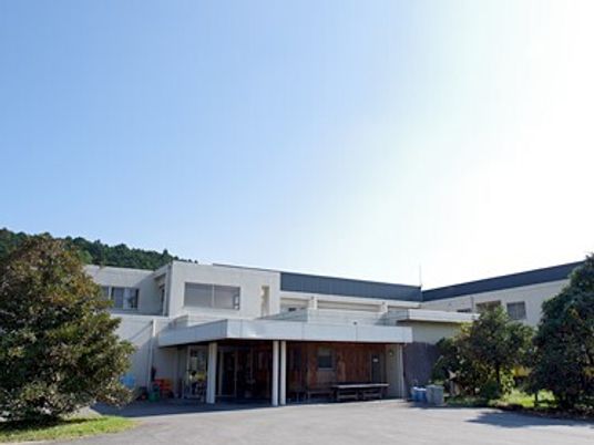 青空が広がる自然に囲まれた場所にある建物。ケアハウスなめがわの外観写真