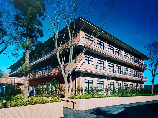 ブラウン系の３階建ての建物の周りには草木が植えられ、各フロアにベランダがあり、明るい雰囲気。