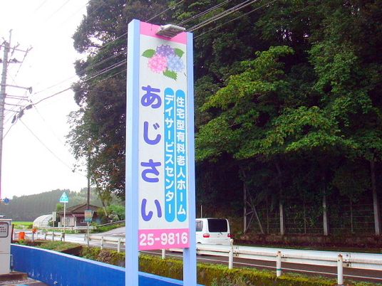 住宅型有料老人ホームあじさいの看板。看板の奥に林のようなスペースが見えている