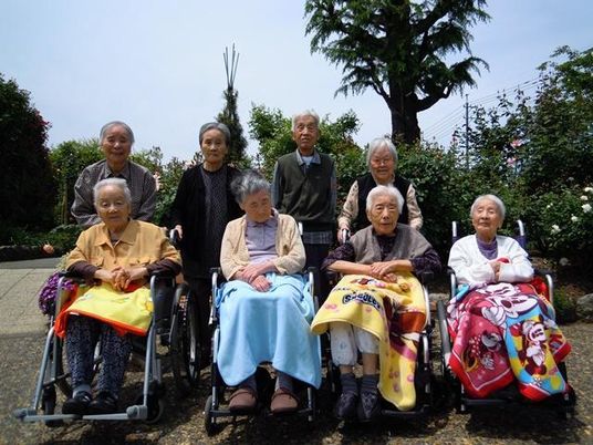 車いすに乗っている人と立っている人がきれいに並んで写真に納まっている様子