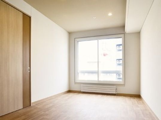 フローリングの居室。大きな窓が付いたシンプルな部屋。