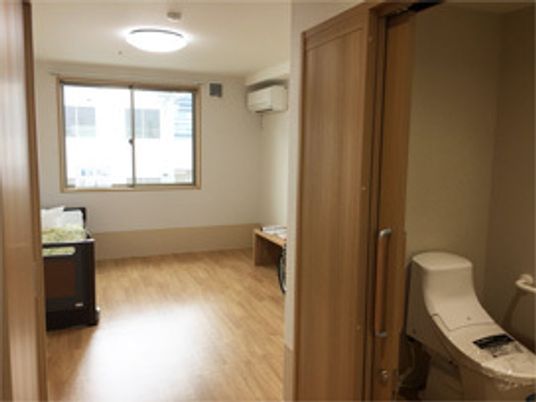 スライド式のドアが設置されたトイレが設置されたフローリングの部屋にはエアコンもついている。