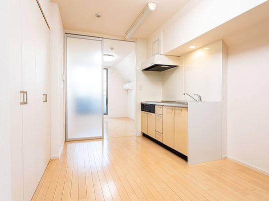 フラットフロアのフローリングの部屋にはIHクッキングヒーター付きのキッチンがあり、収納スペースも付いている。