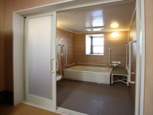 バリアフリーの浴室の様子。手すり、シャワースペース、腰かけ用のスペースがある