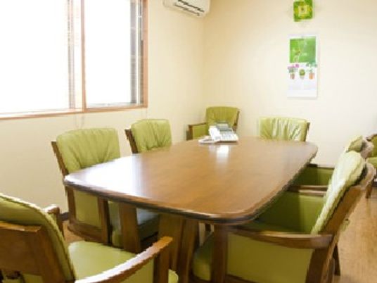 座り心地の良さそなグリーンのいすが長方形のテーブルを囲んで置かれている。日当たりがよく明るい部屋。