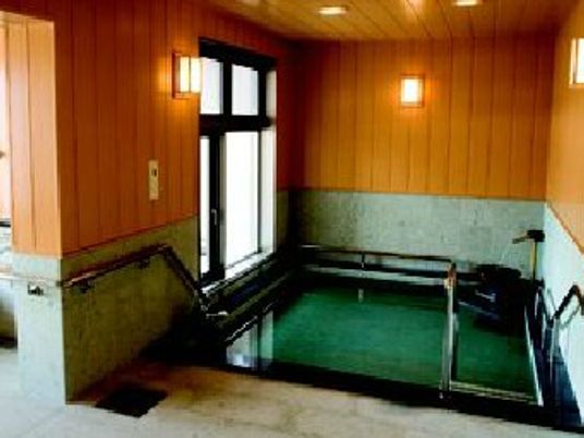 和の趣を大切にした浴室。大きな浴槽の周りには木でできた壁があり、手すりも設置されている。