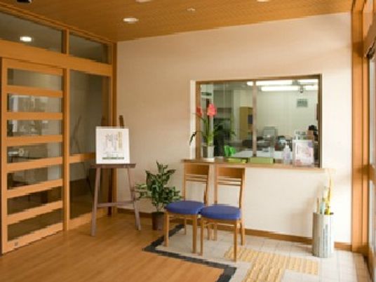 受け付けには花や観葉植物が置かれ、明るいスペース。奥にはスタッフの姿が見える。