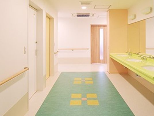 白い館内には手すりが設置され、廊下のフロア部分にはカラフルな模様が描かれ、洗面台は目立つ黄色。