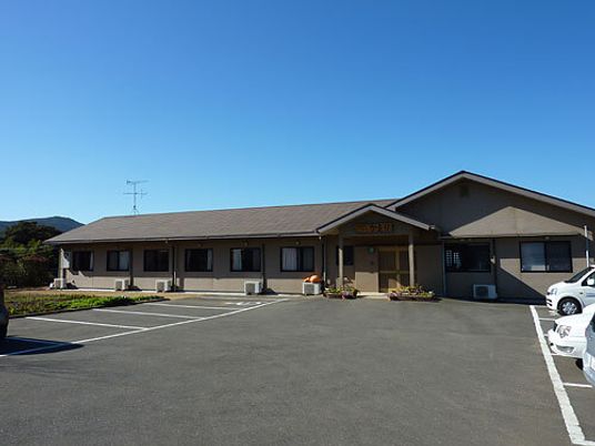 大きな駐車場が付いた平屋建てのホームには三角の屋根が付き、周辺には緑が多い。