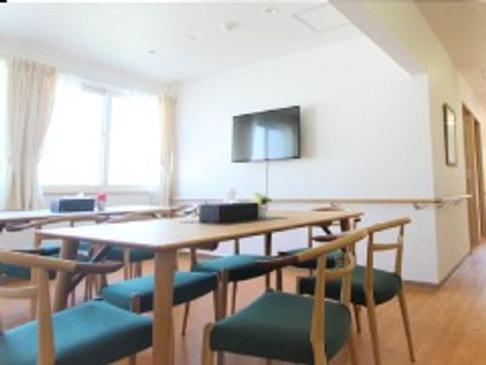 木製のダイニングテーブルセットが複数置かれた食堂には、壁掛けテレビもある。